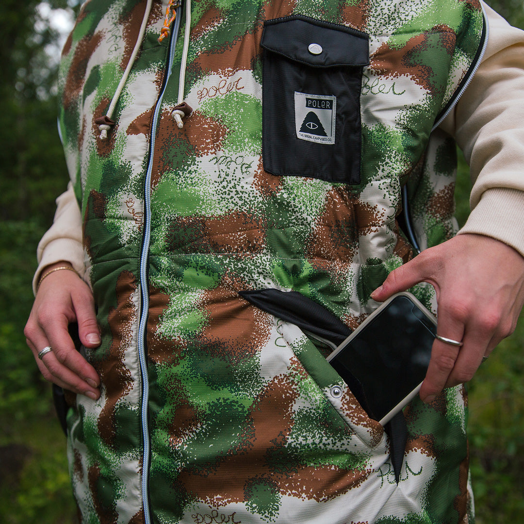 Close-up of a green and brown camo Napsack as a hand slides a phone into its side pocket