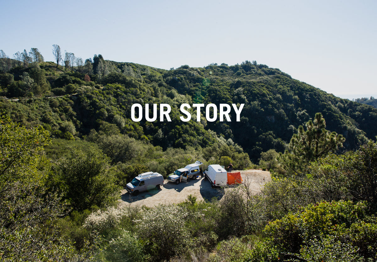 "Our Story" over vans and an orange tent parked at a clearing on a forested green hillside